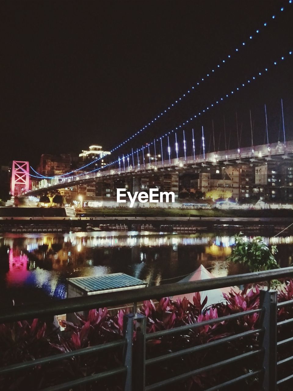 BRIDGE OVER RIVER IN CITY AT NIGHT