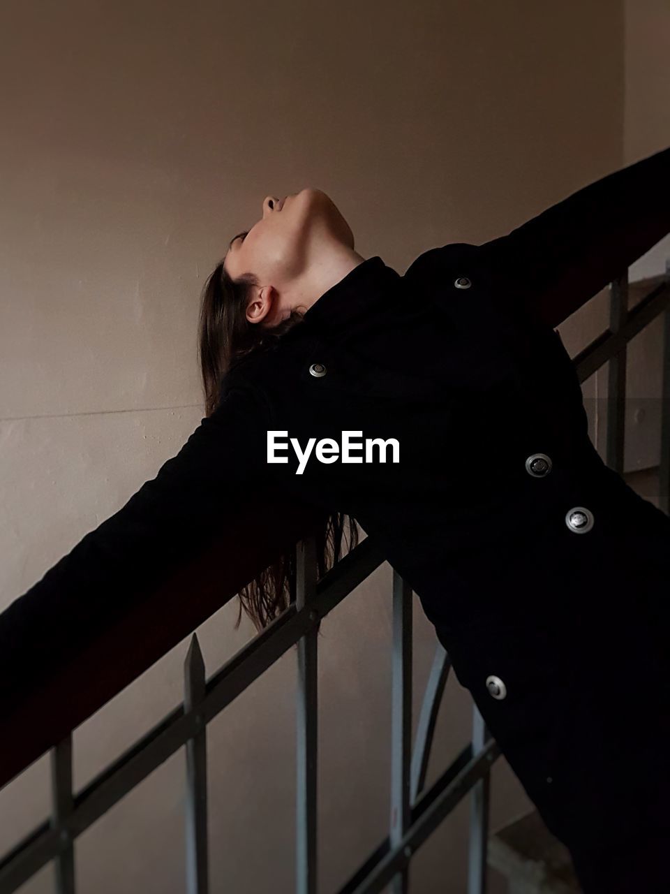 Woman leaning on railing against wall