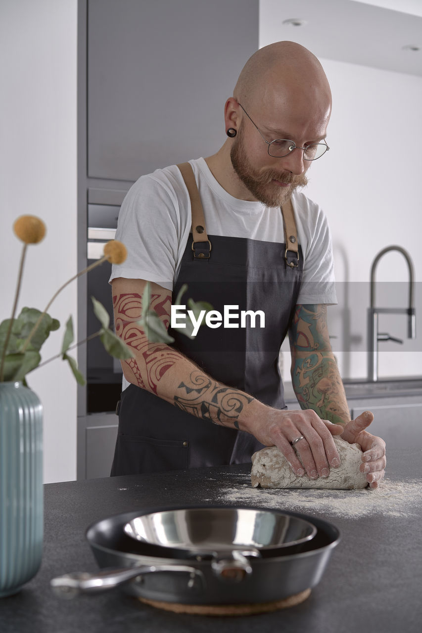 Man kneading rye sourdough on floured surface