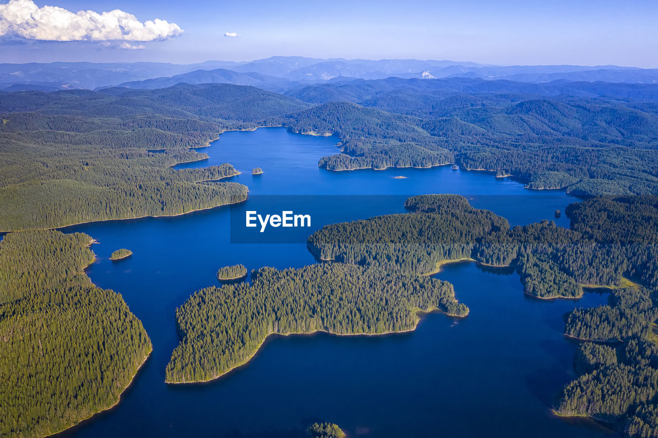 HIGH ANGLE VIEW OF LAKE AND MOUNTAINS AGAINST BLUE SKY