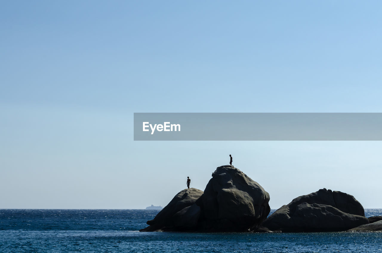 View of rock in sea against clear sky