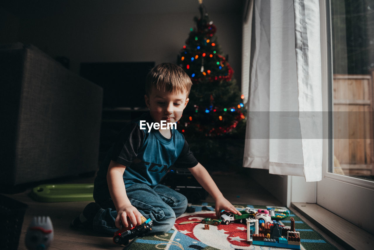 Full length of boy playing with toy against christmas tree at home