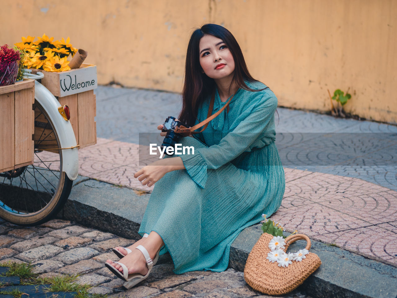 PORTRAIT OF YOUNG WOMAN SITTING ON WALL OUTDOORS