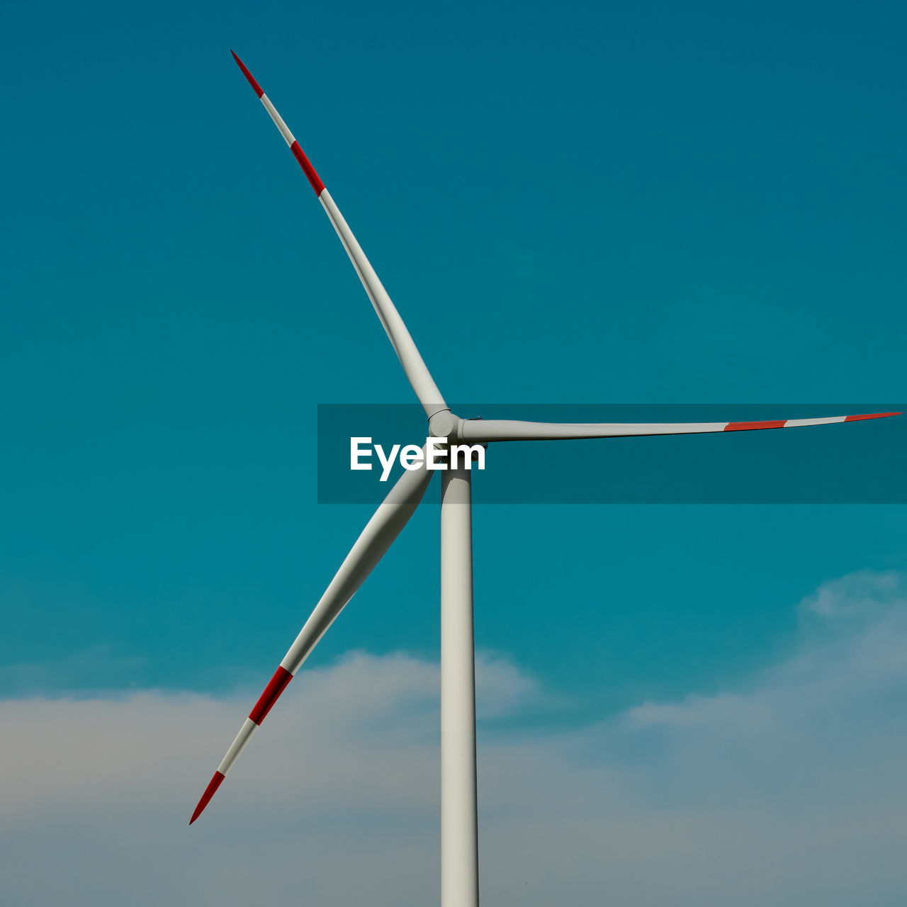 Wind turbine in front of a blue sky with white clouds