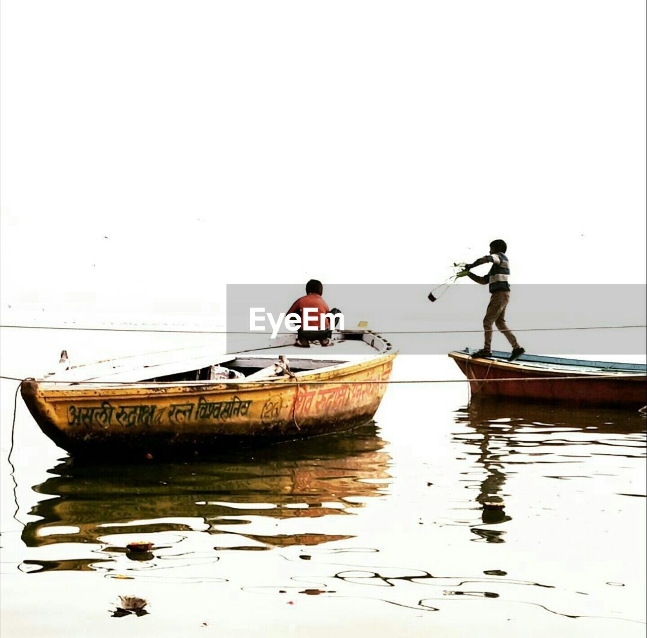 Boys on boat in sea against clear sky