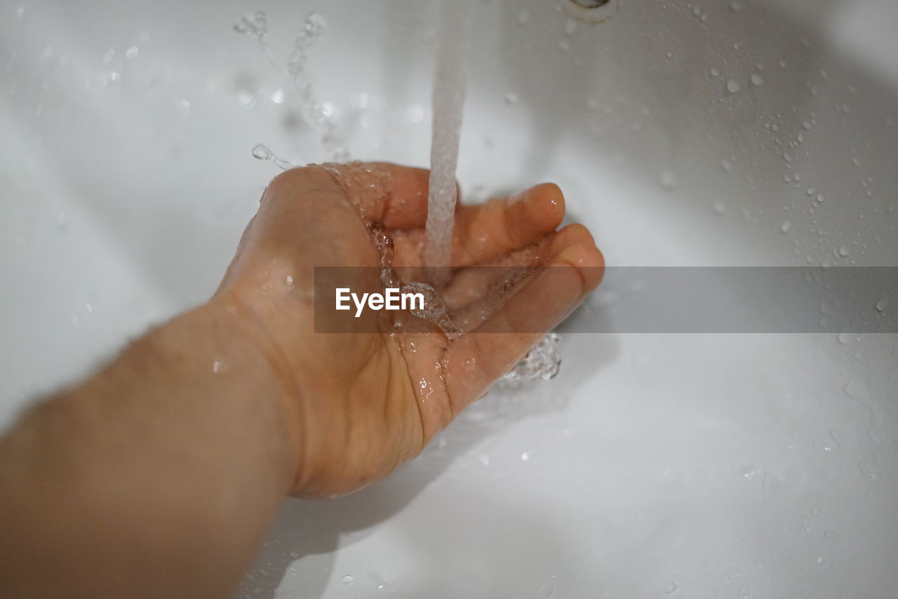 CLOSE-UP OF WET HAND IN BATHROOM