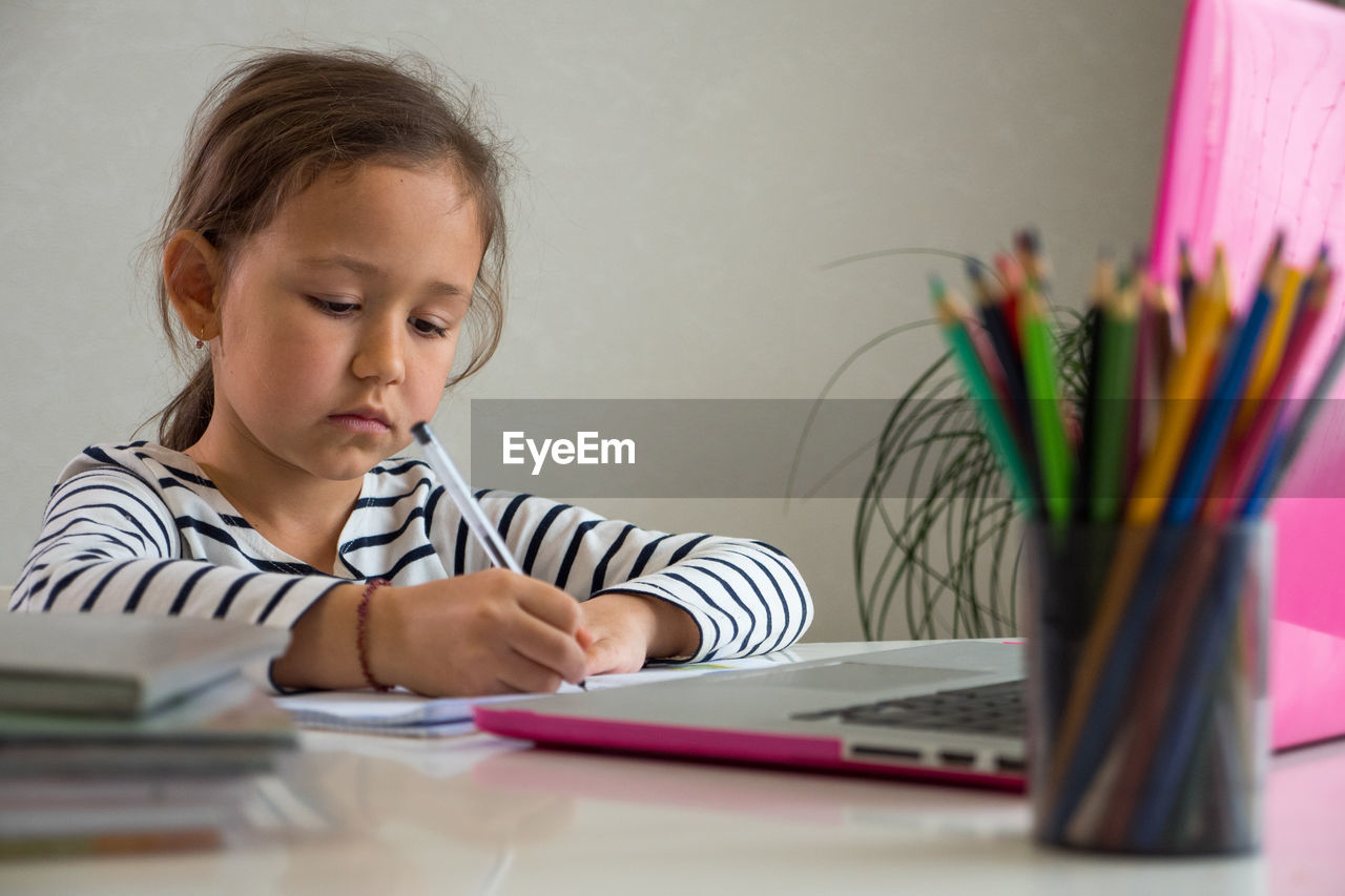 Cute girl writing in book at home