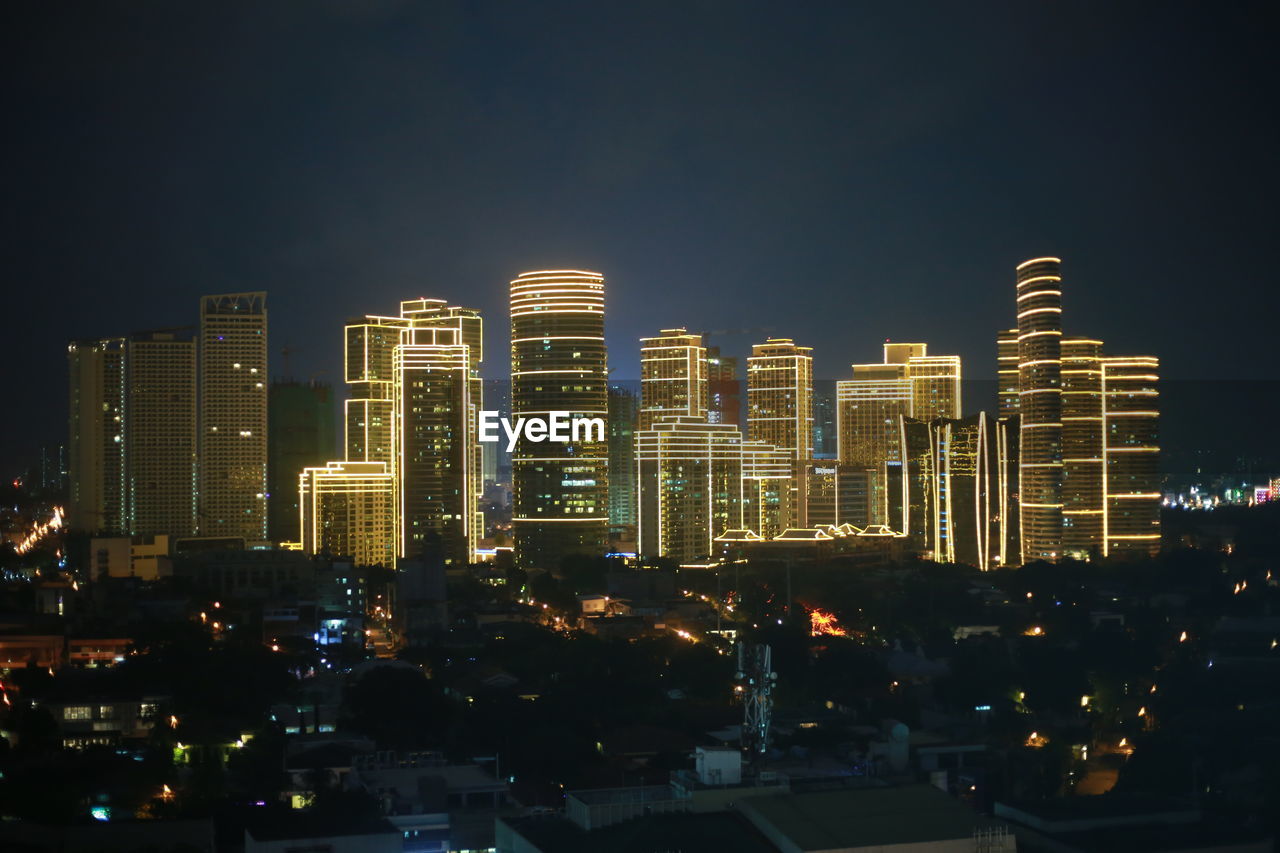 ILLUMINATED MODERN BUILDINGS AGAINST SKY AT NIGHT