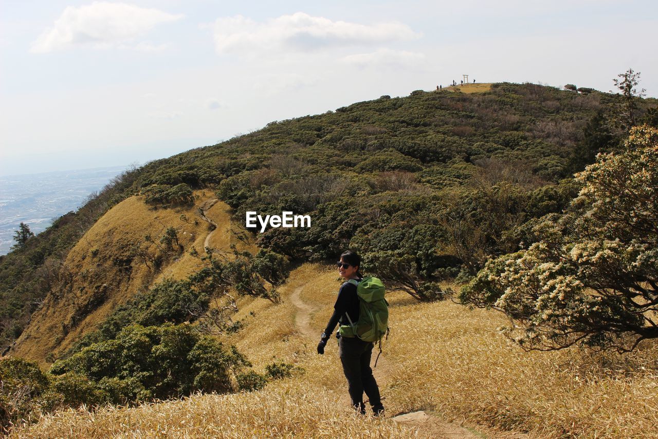 FULL LENGTH REAR VIEW OF MAN STANDING ON MOUNTAIN