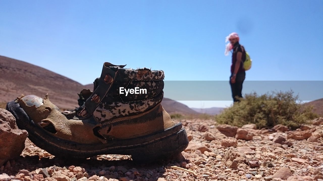 Man looking at abandoned shoe against sky