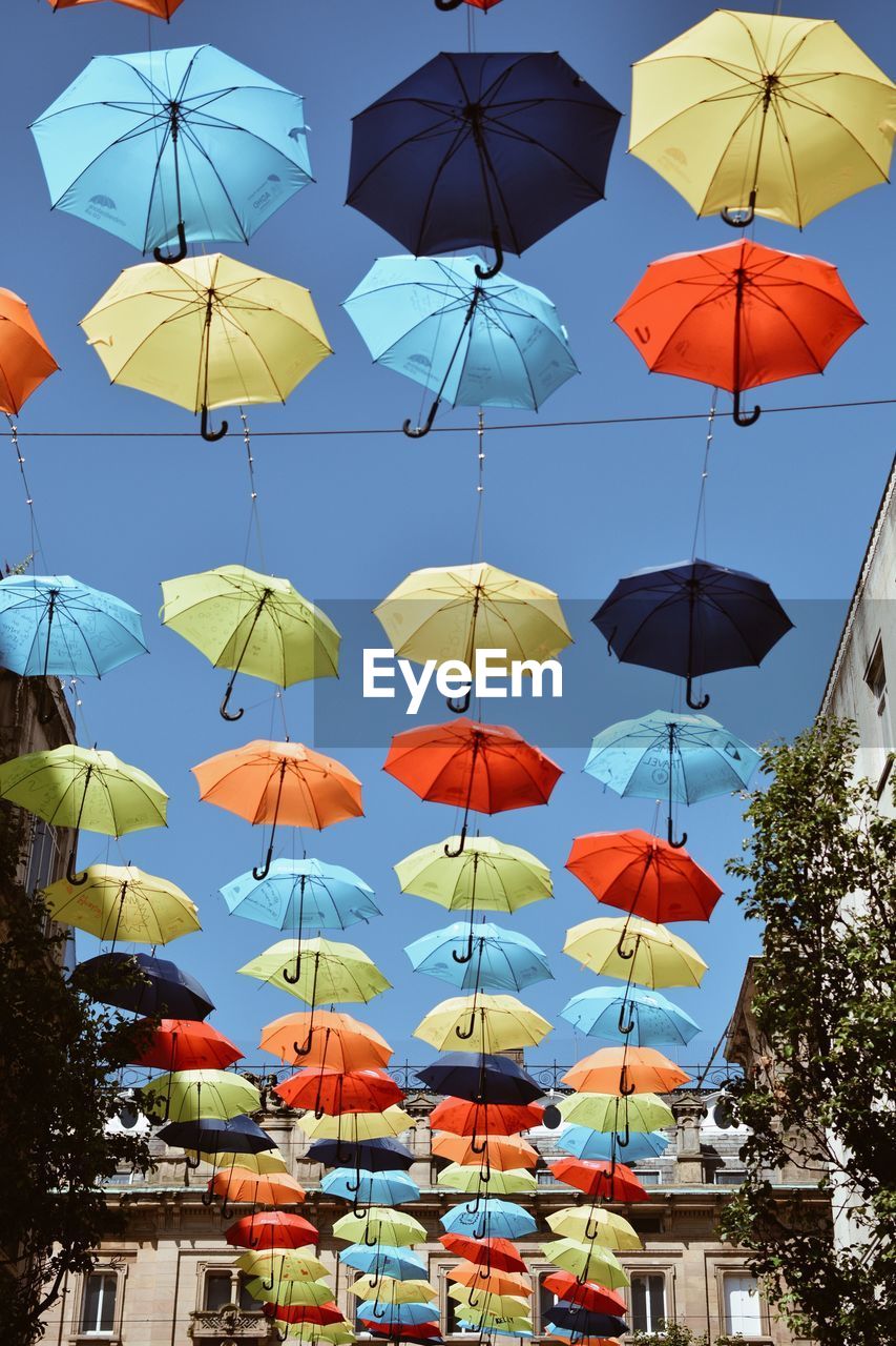 Low angle view of umbrellas hanging against clear sky