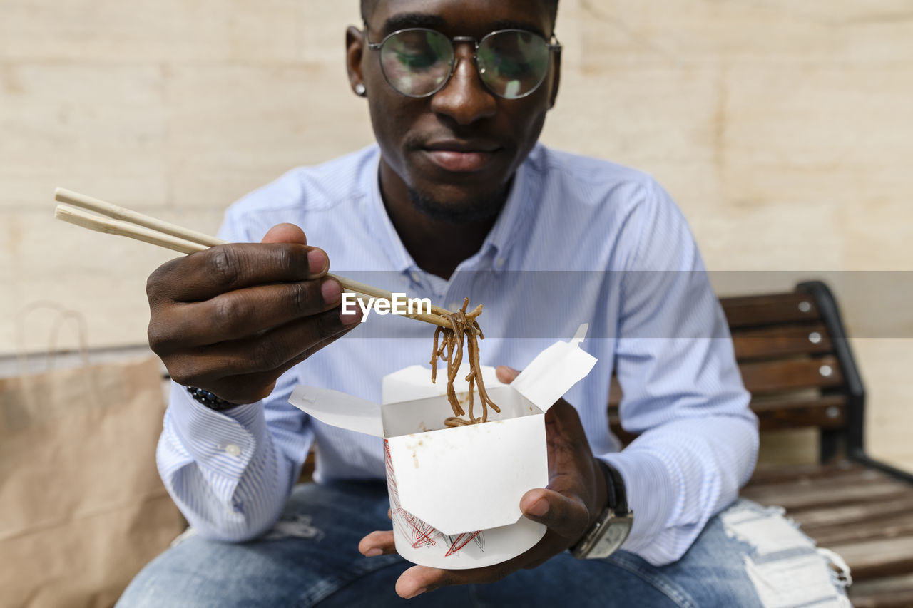 Man having noodles with chopsticks