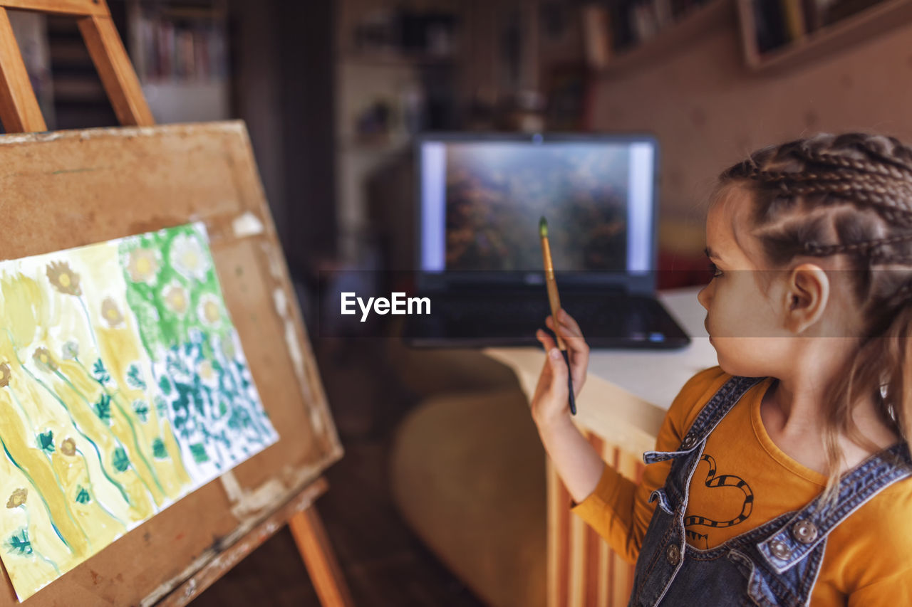 Side view of girl painting at home