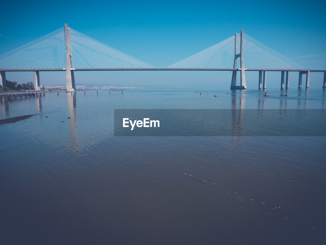 Bridge over calm sea against clear sky