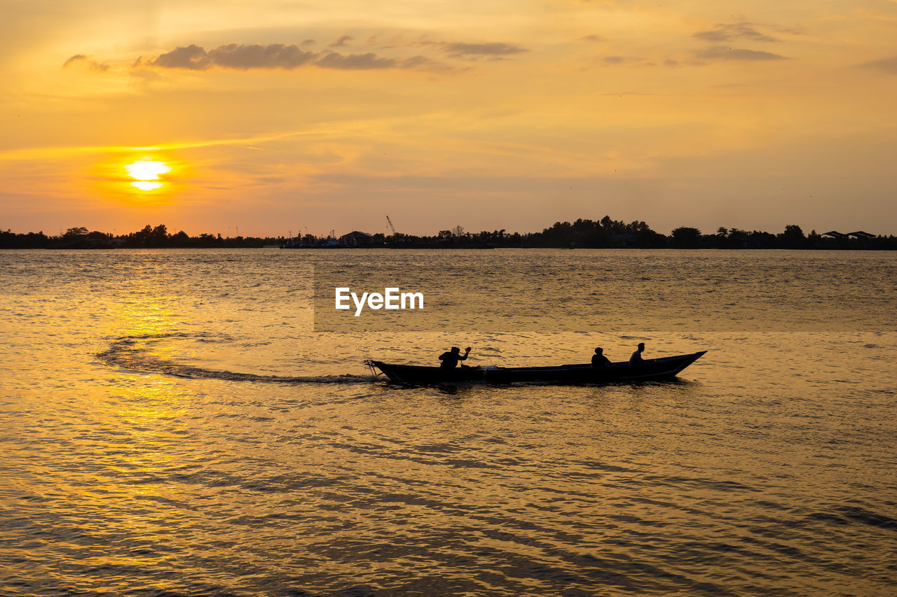 Silhouette of a boat on river at orange sunset time