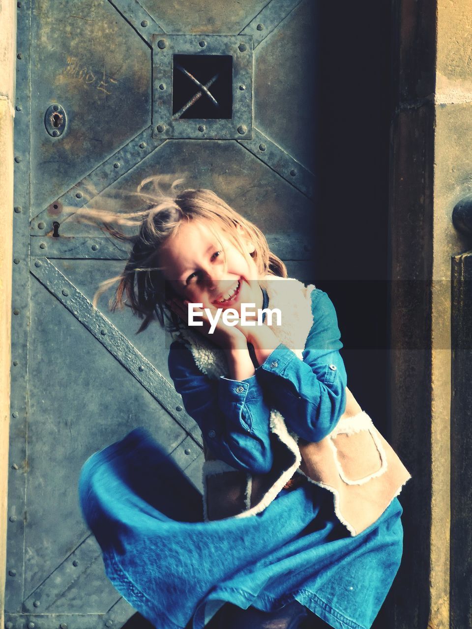 Portrait of cute smiling girl standing against closed door