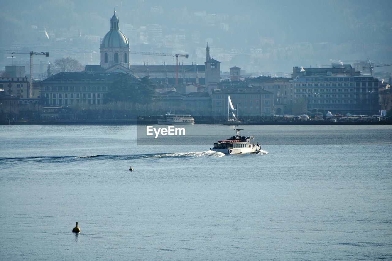 Sailboat sailing on lake against buildings in city