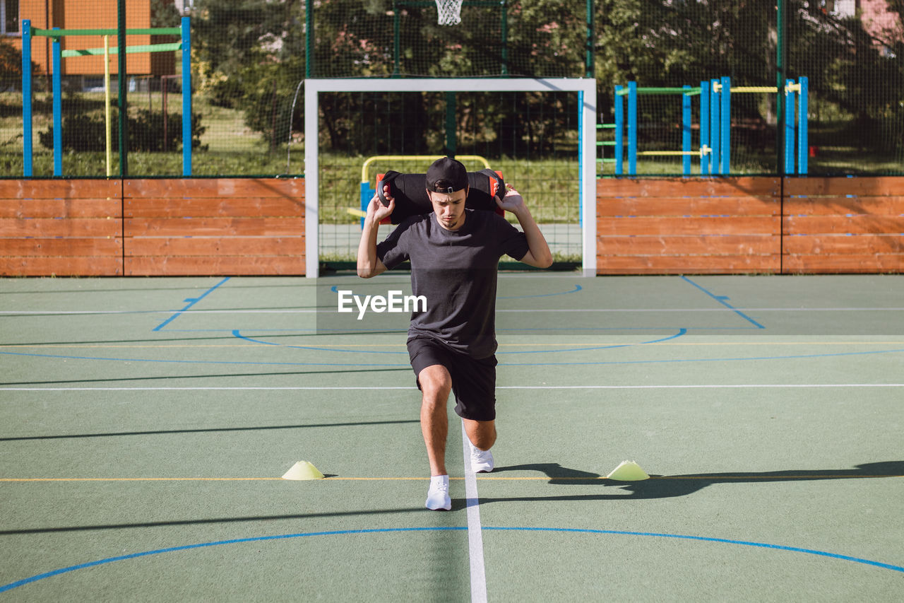 Athlete with a barbell on his back performs a lunge to strengthen the trunk and lower part of body