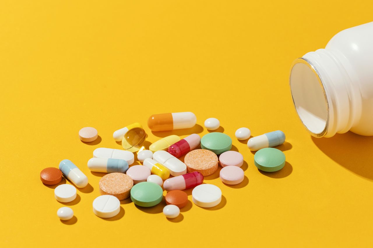 pills spilling from bottle over yellow background