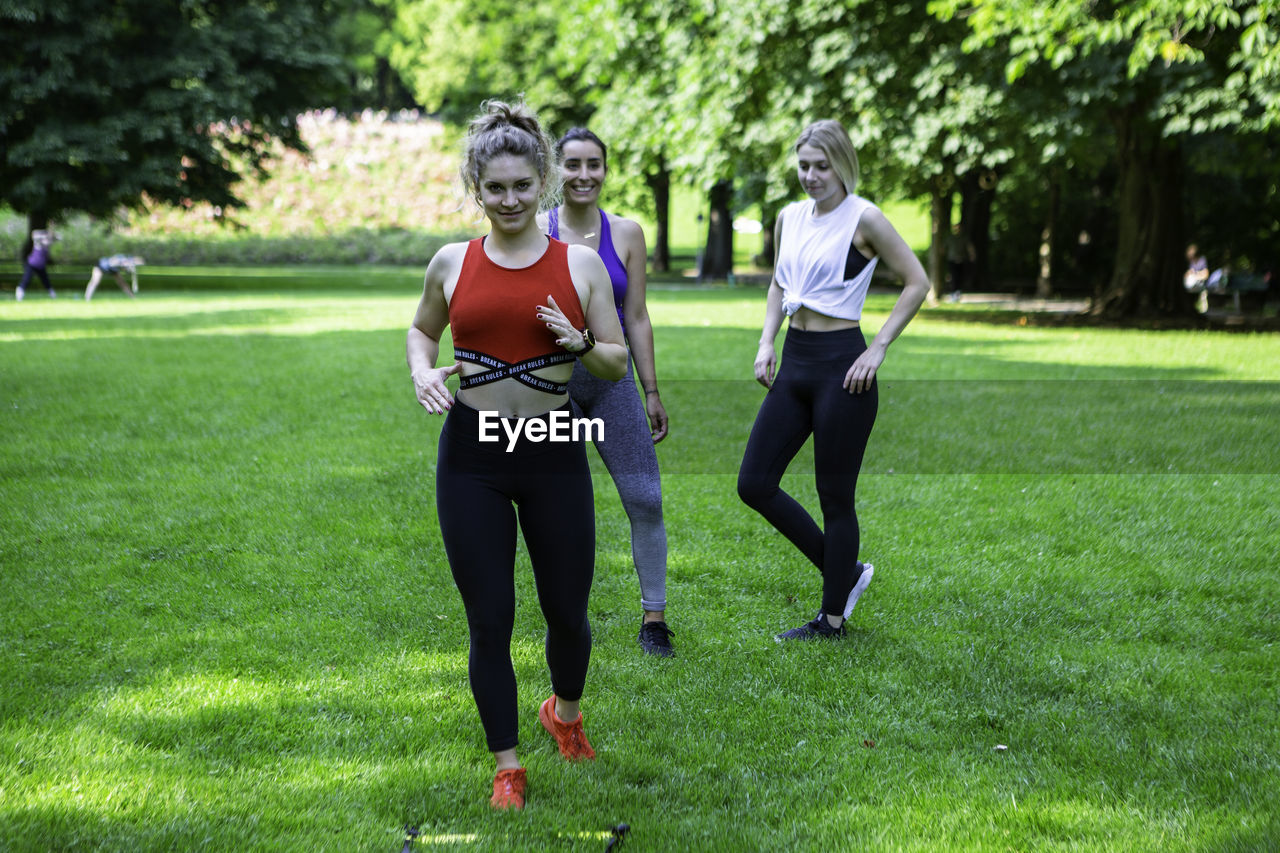 Three ladies wearing sports clothing train together in a park in munich, germany.