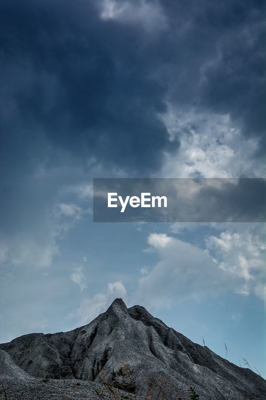 Low angle view of volcanic mountain against sky