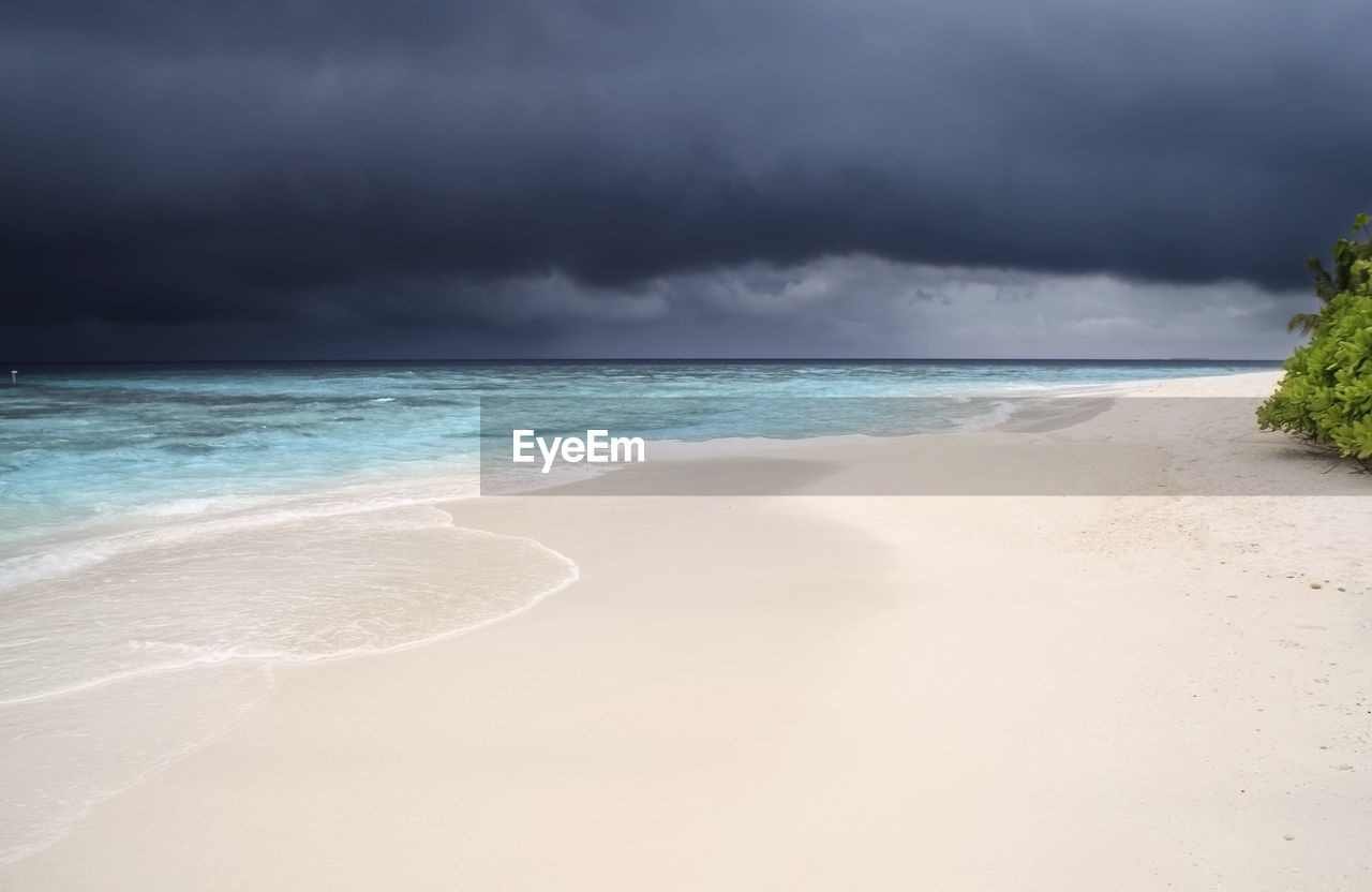 Scenic view of beach against cloudy sky