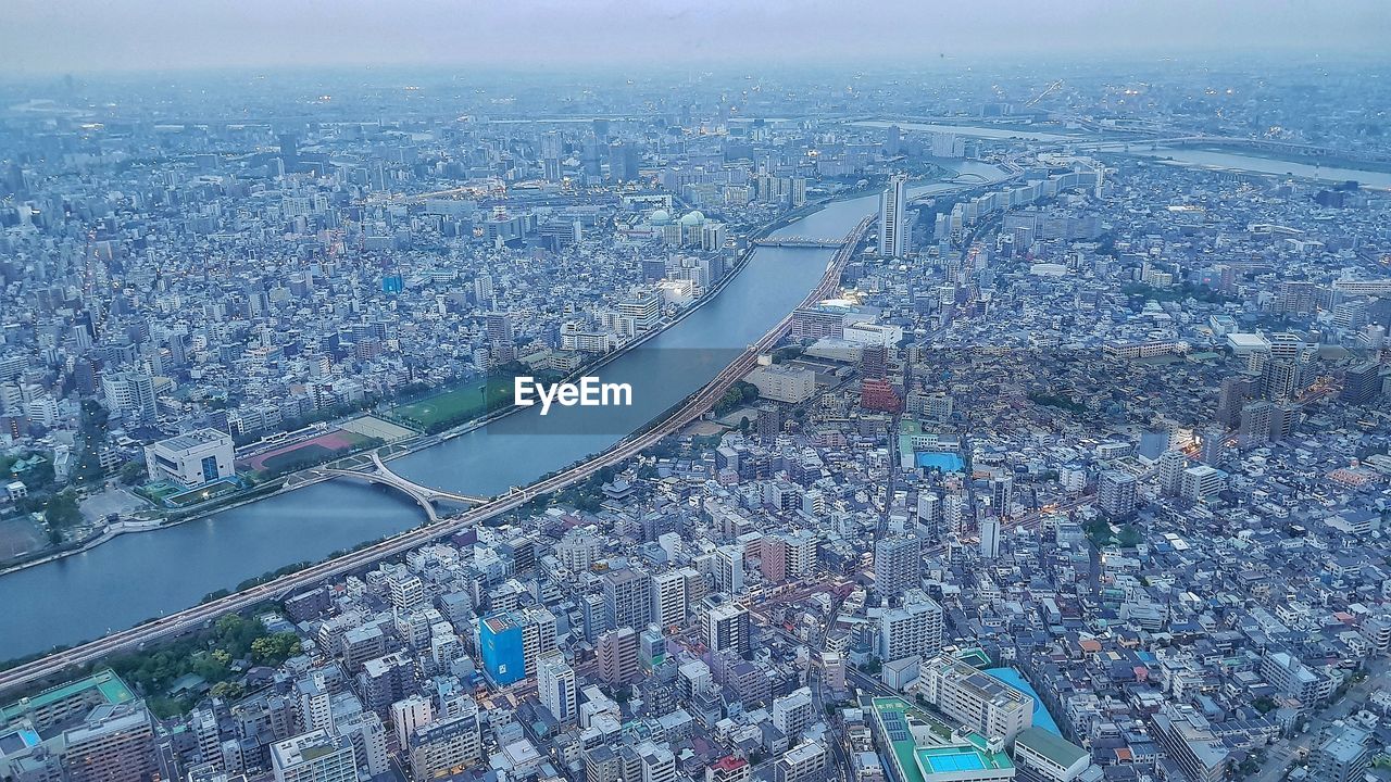 HIGH ANGLE VIEW OF ILLUMINATED CITY BY RIVER