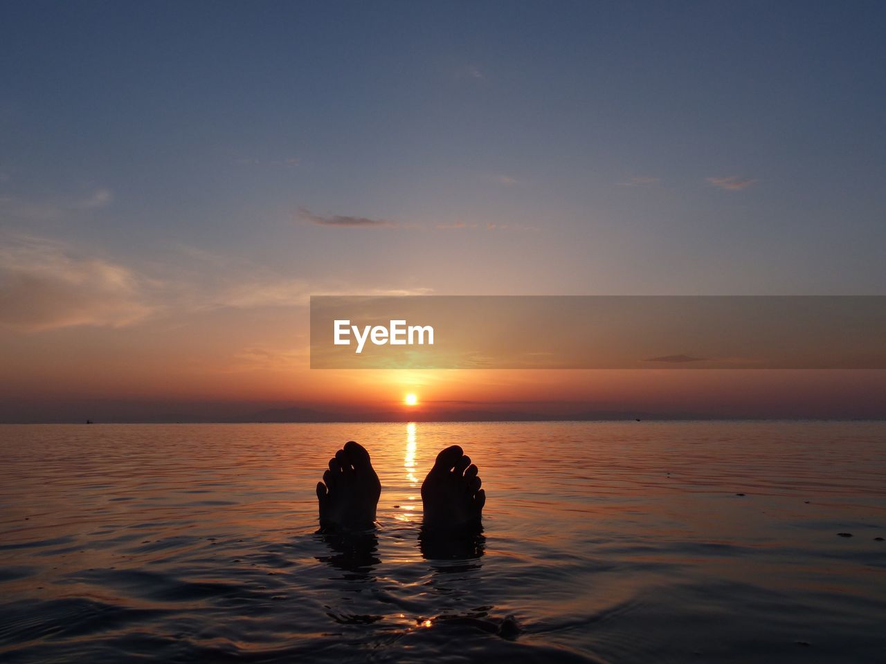 PEOPLE IN SEA AGAINST SKY DURING SUNSET