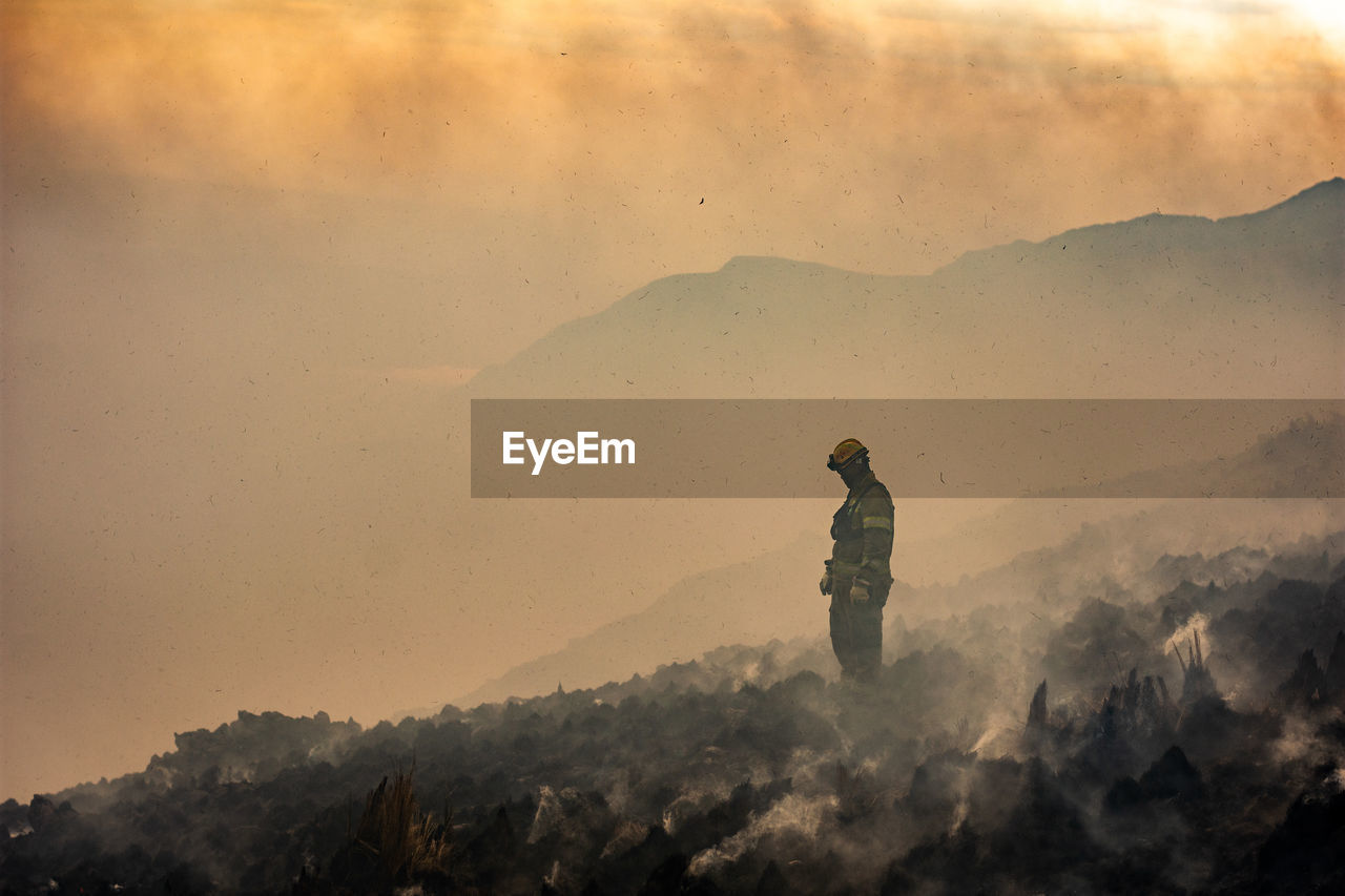 Man standing on mountain against sky during sunset