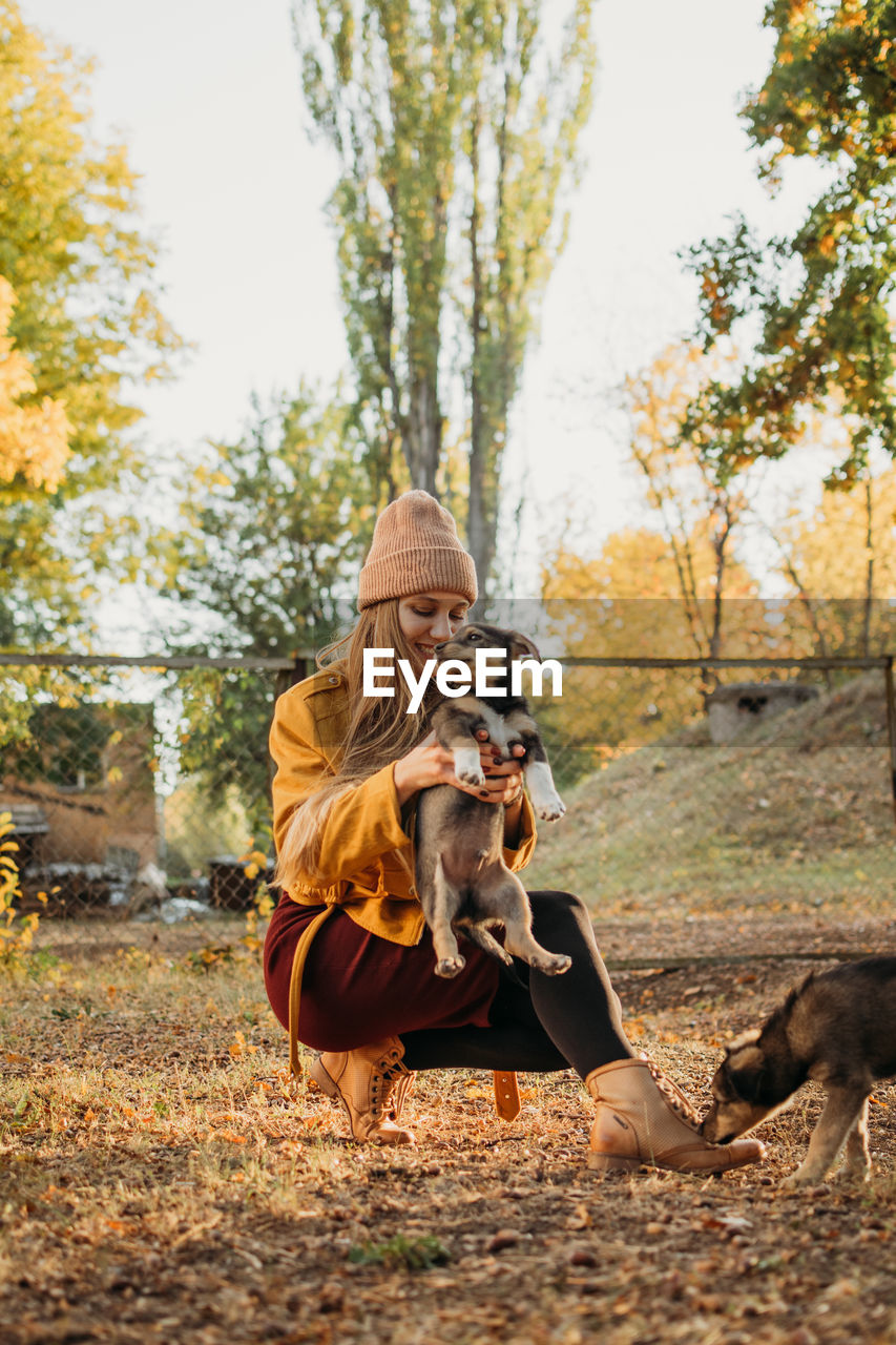 Pet love. volunteer woman plays with homeless puppies in the autumn park. authentic moments of joy