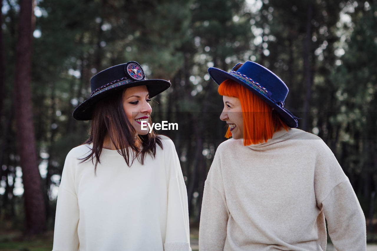Smiling women wearing hat standing in forest