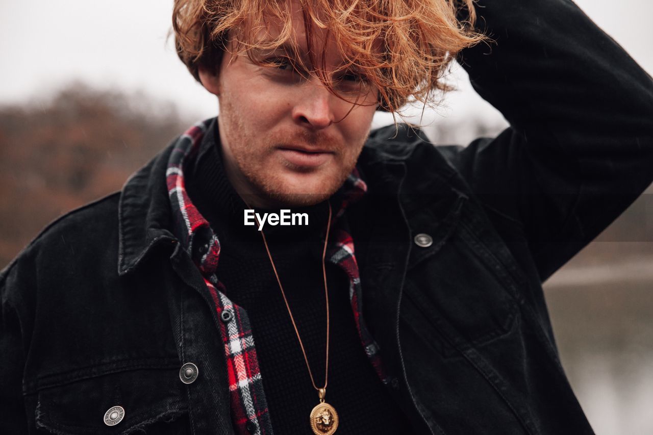 Portrait of young fashionable man with hand in hair
