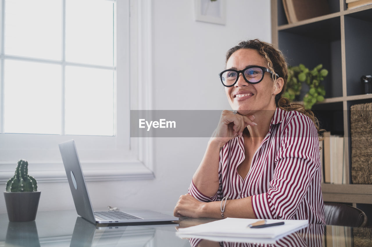 businesswoman using laptop while sitting on table in office