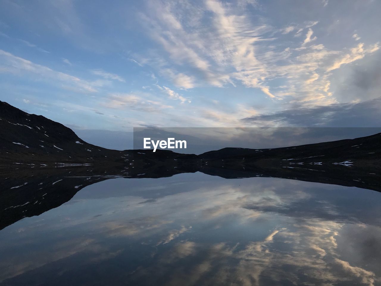 Scenic view of lake by mountain against sky