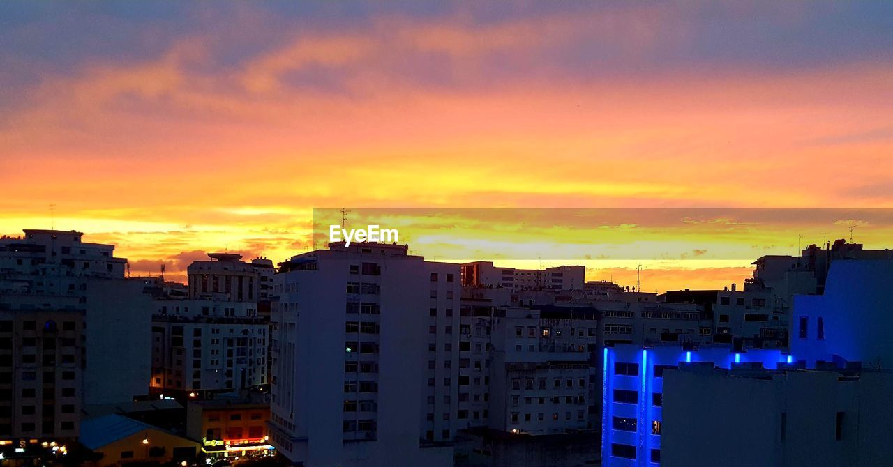 Buildings against dramatic sky during sunset