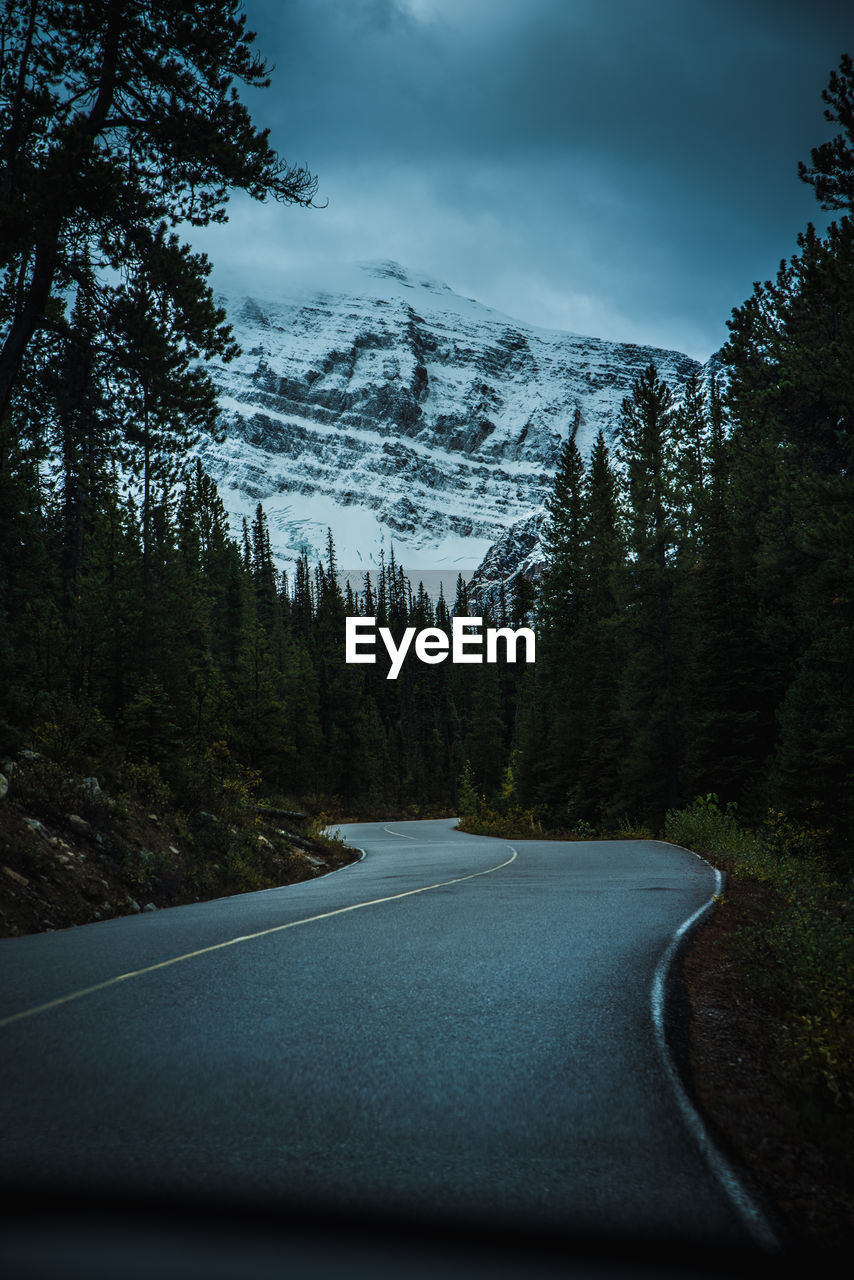 Winding road leading towards snowcapped mountain