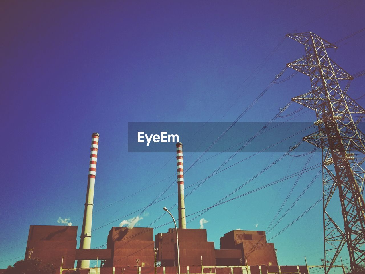 Low angle view of electricity pylon with buildings in background