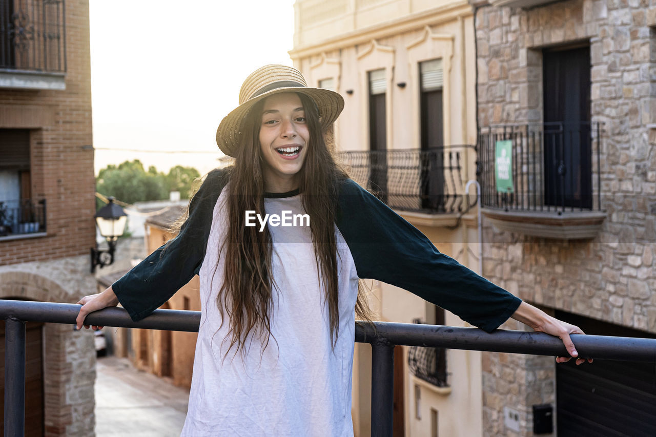 Portrait of smiling young woman standing against railing