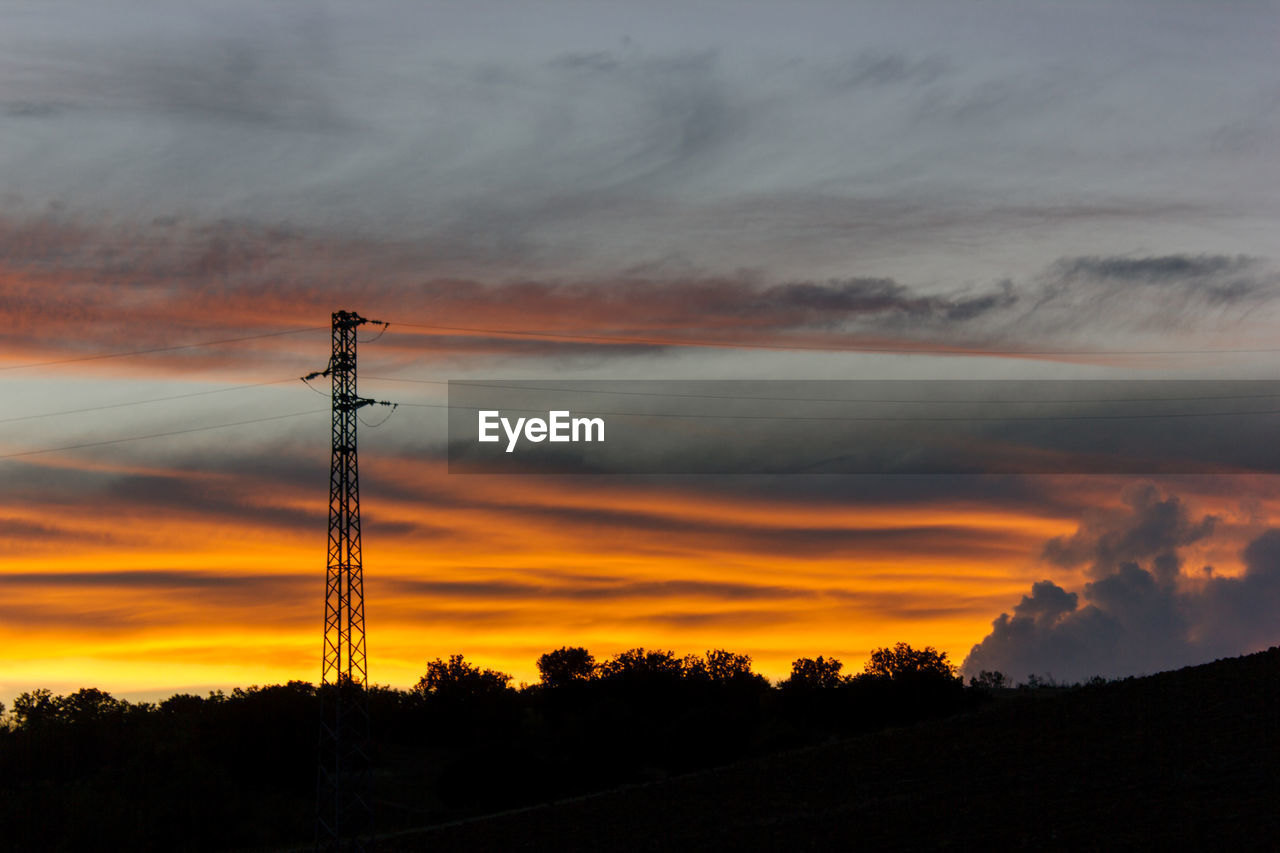 SILHOUETTE ELECTRICITY PYLONS AGAINST SKY DURING SUNSET