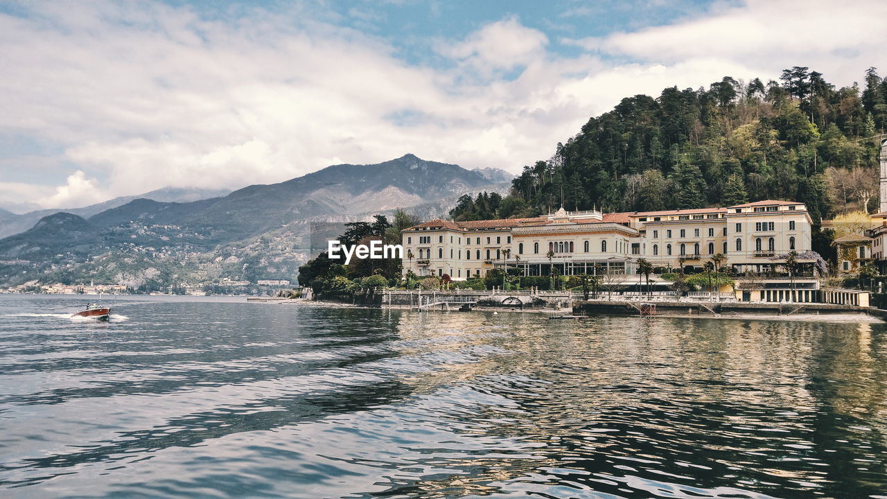 Building by lake against cloudy sky