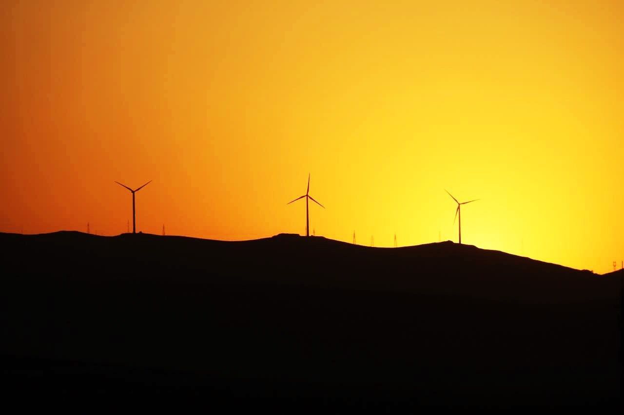 SILHOUETTE OF WIND TURBINES ON LANDSCAPE AGAINST SKY