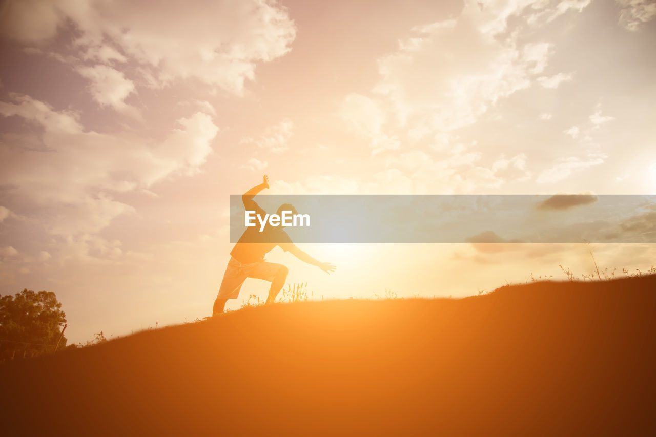 Silhouette man standing against sky during sunset