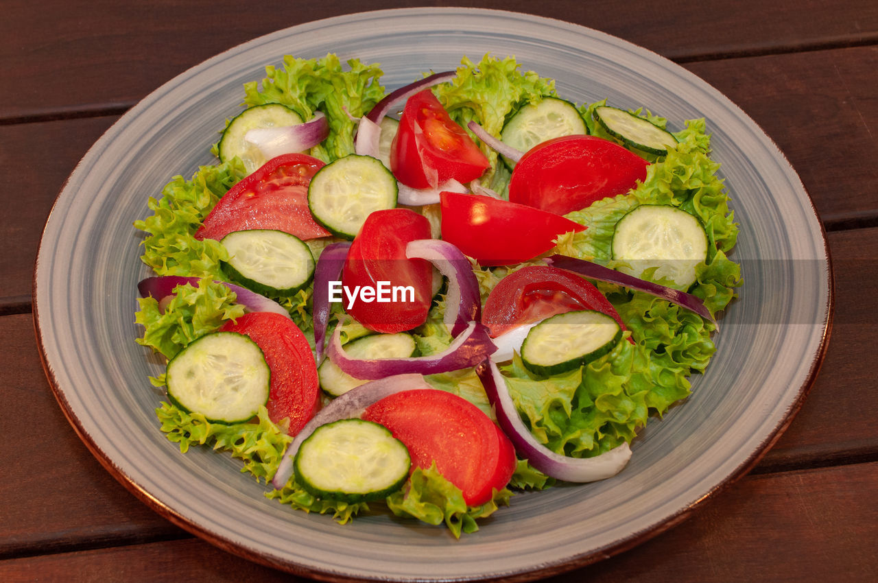 food, food and drink, healthy eating, vegetable, wellbeing, salad, fruit, freshness, tomato, dish, wood, lettuce, indoors, vegetarian food, no people, produce, studio shot, cucumber, plate, cuisine, slice, directly above, cheese, high angle view, meal, organic, bowl, still life, dairy, table, avocado