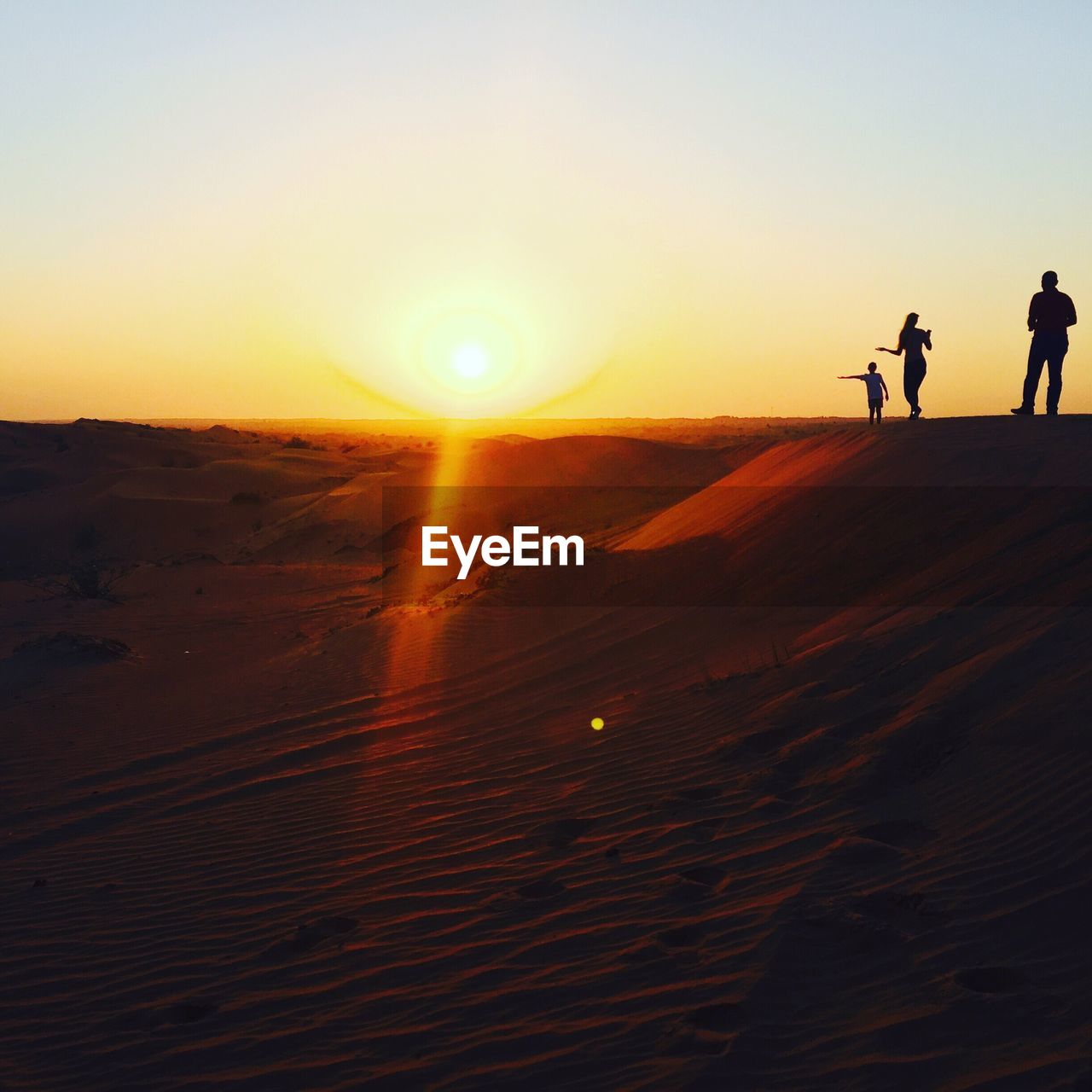 Silhouette people walking on desert against clear sky during sunset