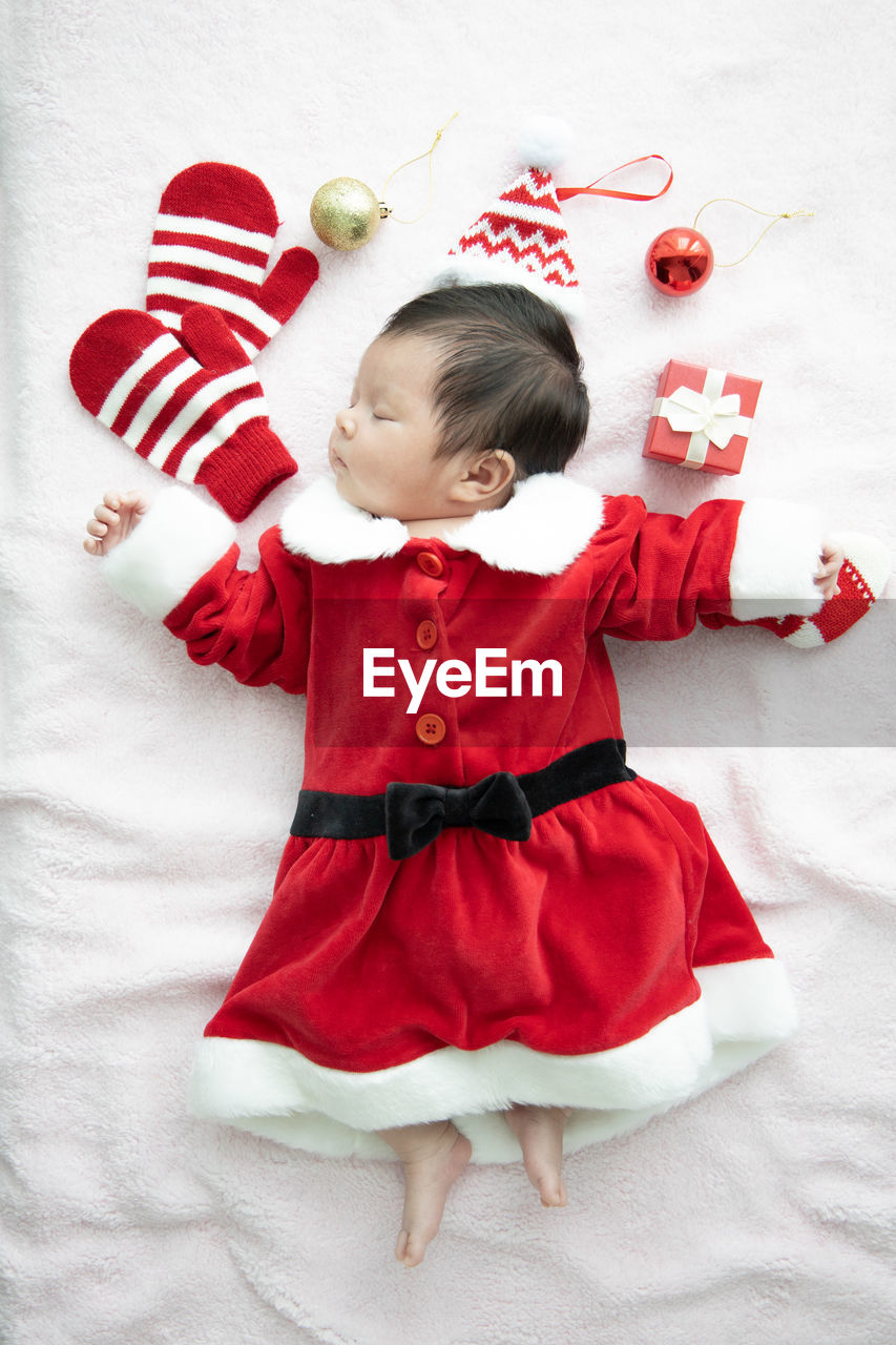 Directly above shot of baby girl wearing santa claus costume sleeping on bed at home