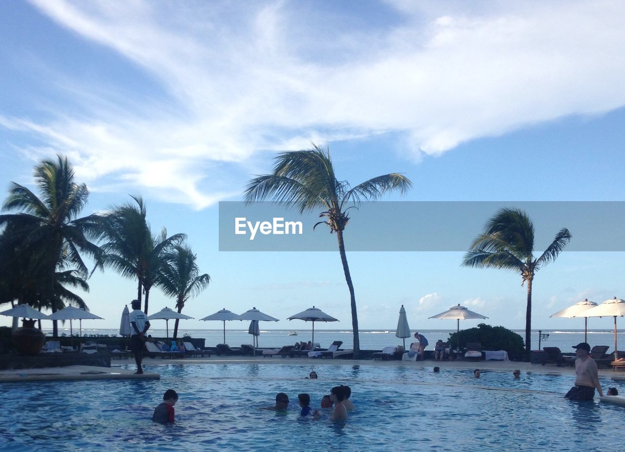 People enjoying in swimming pool near sea