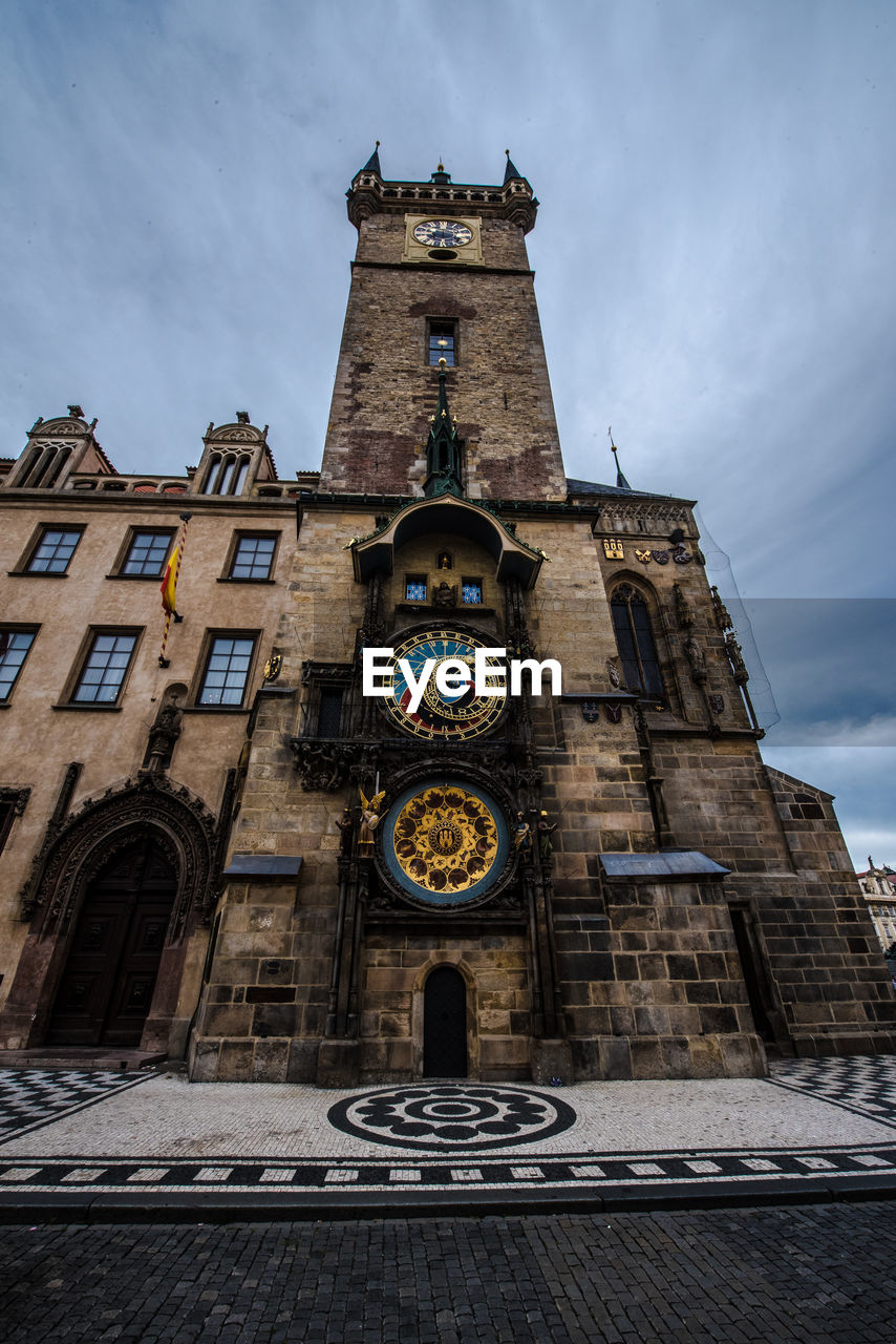 Low angle view of clock tower amidst buildings against sky