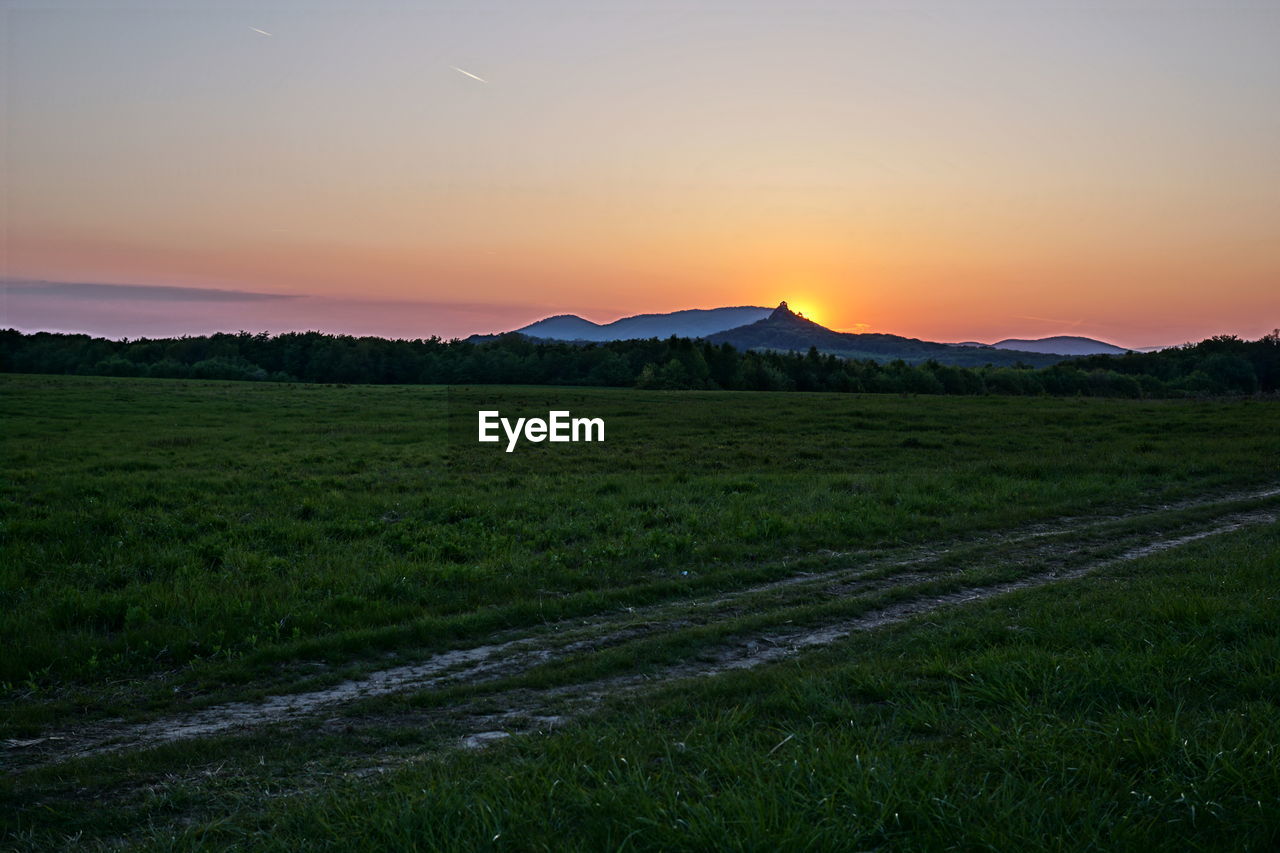 SUNSET OVER GRASSY FIELD