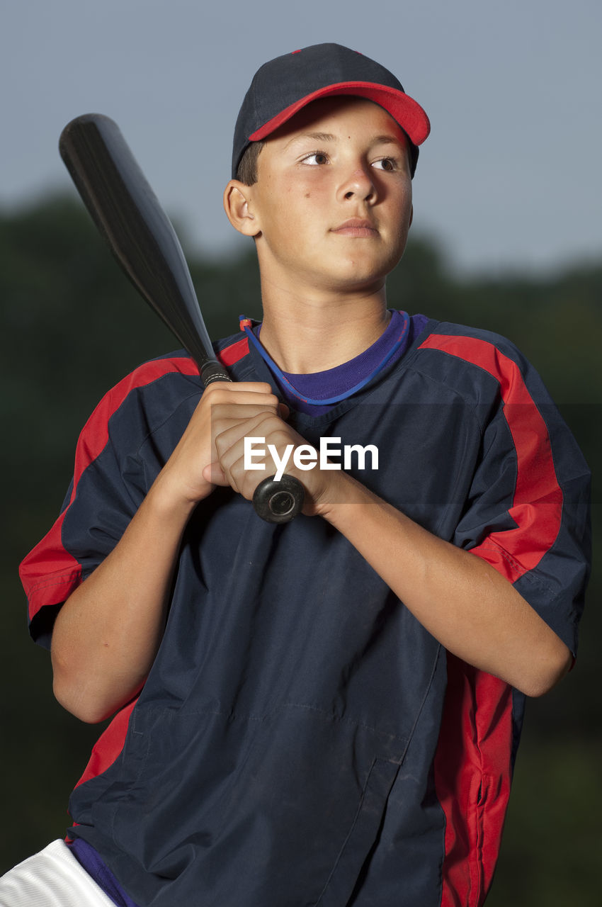 Portrait of a baseball player holding his bat wearing a warm up jacket