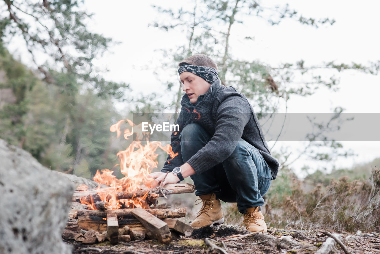 Man putting sticks on a campfire outdoors in sweden